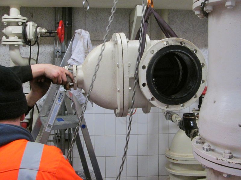 Monteur van Hydrotec werkt aan een groot leidingonderdeel dat aan een takel hangt